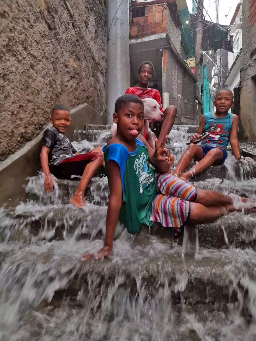 agrandeartedeserfeliz.com - Foto de crianças na chuva e cãozinho sorrindo em comunidade do Rio viraliza: 'Todo mundo feliz'